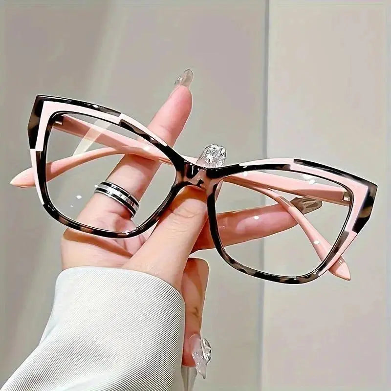Pink cat-eye reading glasses with patterned rims and pink temples, held in one hand